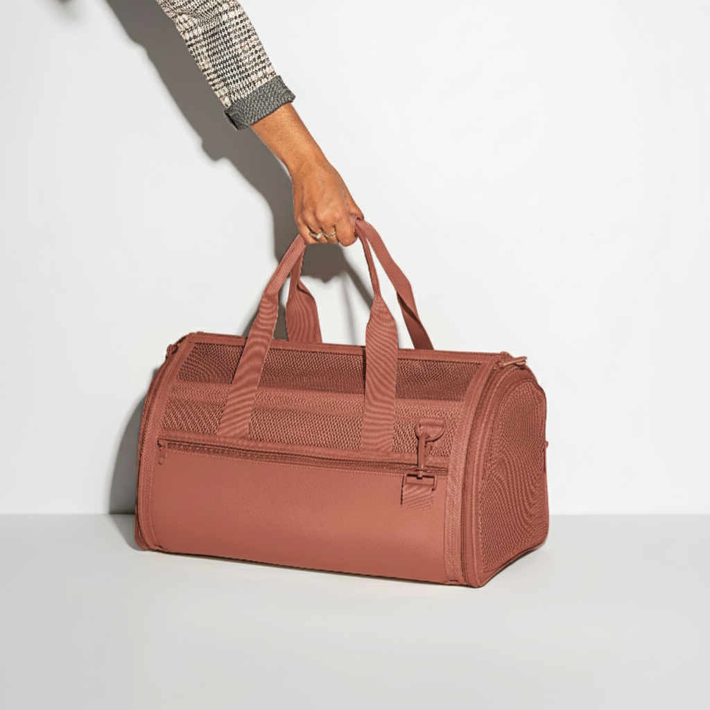 Person holding a pink duffel bag against a white background