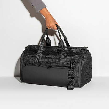 Black pet carrier for dogs and cars held by a hand on a light gray background